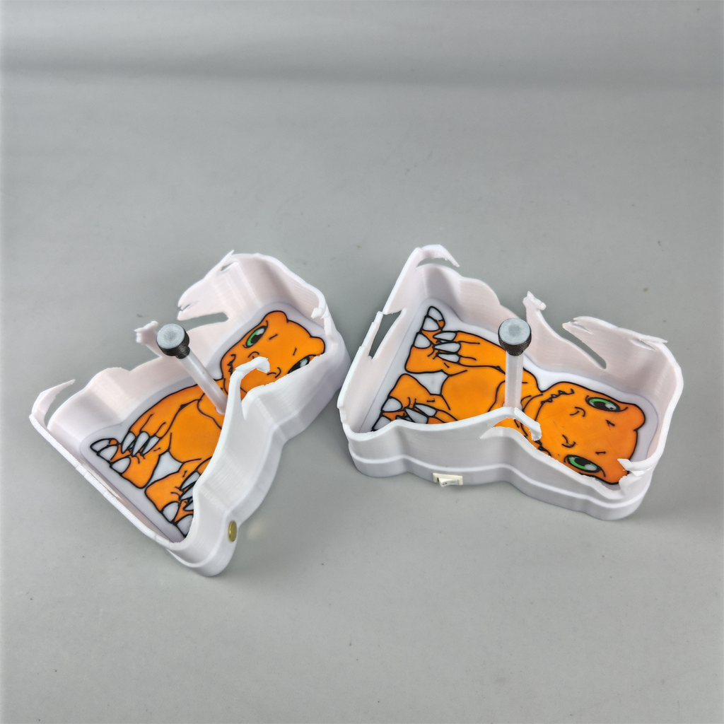 Two Agumon-inspired shadow projection lamps from behind showing orange dinosaur artwork and sculpted white back structures