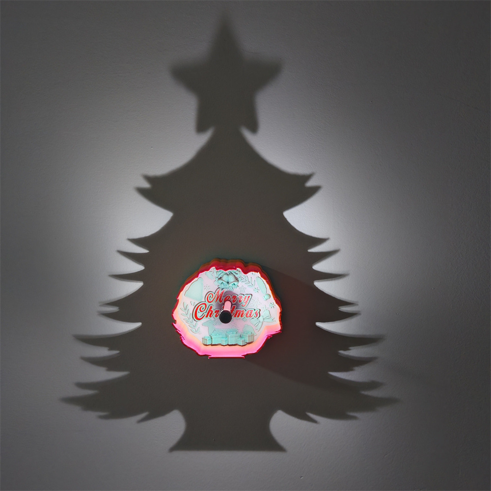 Christmas tree star shadow lamp projecting a large Christmas tree silhouette on a wall with a colorful Merry Christmas decoration at center