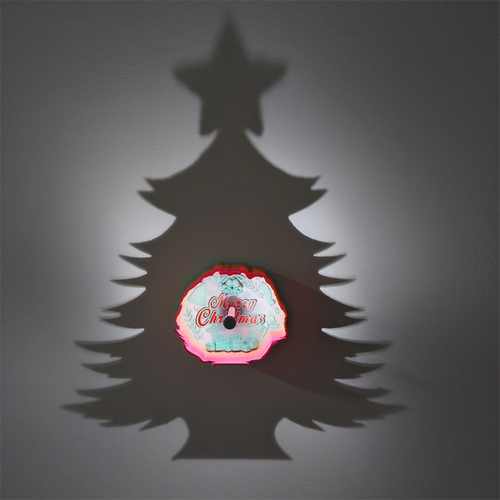Christmas tree star shadow lamp projecting a large Christmas tree silhouette on a wall with a colorful Merry Christmas decoration at center