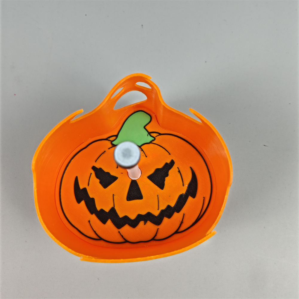 Close-up back detail of orange jack-o'-lantern pumpkin shadow lamp with carved face and green stem
