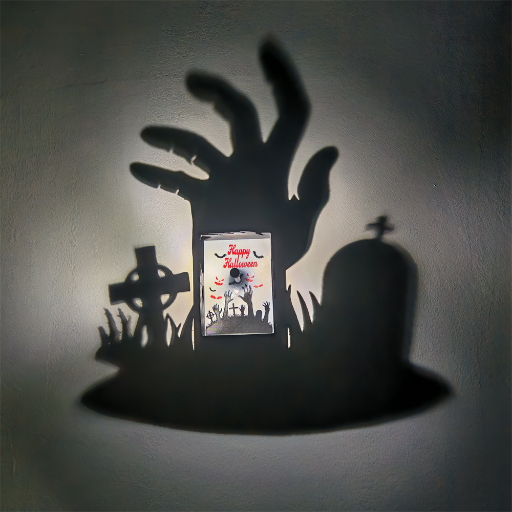 Halloween graveyard shadow projection lamp casts a large zombie hand with tombstone and cross graveyard silhouettes on the wall