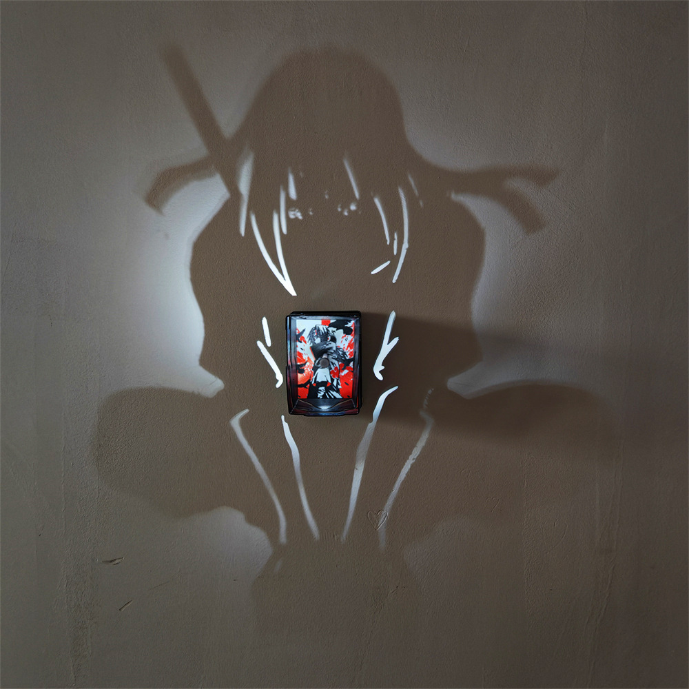 Itachi-inspired anime shadow projection lamp showing a long-haired crouching ninja wall silhouette and a red and black Akatsuki-inspired illustration centerpiece