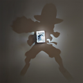 Luffy-inspired anime shadow projection lamp creating a large straw-hat silhouette on a wall with a WANTED poster centerpiece