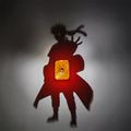 Naruto-inspired shadow projection lamp with glowing orange central light casting large shadow silhouette of an anime shinobi on wall