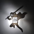 Trafalgar Law-inspired anime shadow projection lamp casting a sword-wielding figure onto a wall with illuminated One Piece WANTED bounty poster centerpiece