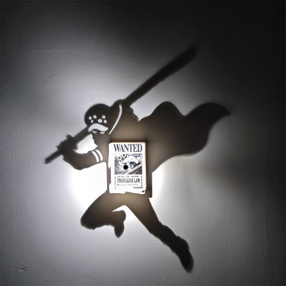 Trafalgar Law-inspired anime shadow projection lamp casting a sword-wielding figure onto a wall with illuminated One Piece WANTED bounty poster centerpiece